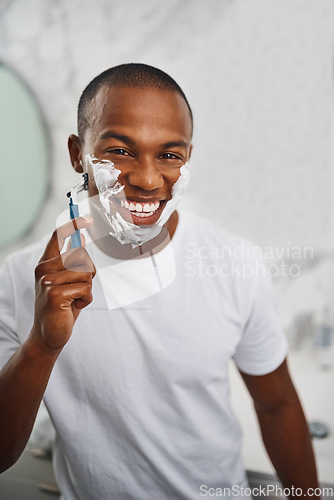 Image of Black man, smile and shaving with blade, soap or grooming in mirror for self care in home bathroom. African guy, foam or cream for facial hair removal, razor or clean for hygiene in morning at house