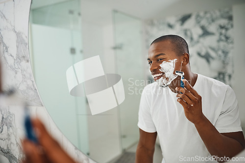 Image of Black man, smile and shaving with razor, foam or grooming in mirror for self care in home bathroom. African guy, soap or cream for facial hair removal, beard or clean for hygiene in morning at house