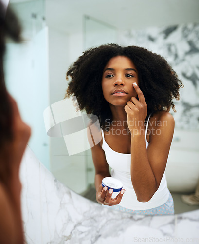 Image of Skin care, bathroom mirror and black woman with lotion, cosmetic product and morning grooming. Health, wellness and dermatology, skincare at home and girl in reflection with cream on face for beauty.