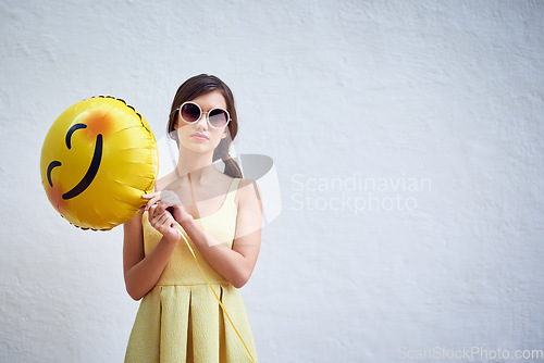 Image of Woman, balloon and sunglasses by wall background in summer with emoji, fashion and mock up space for party. Gen z girl, event and portrait with icon, smiley and yellow dress for spring celebration