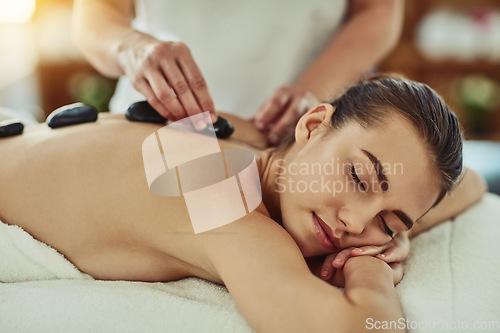 Image of Spa, zen and woman getting a hot stone back massage for luxury, calm and natural self care. Beauty, body care and tranquil female person sleeping while doing a rock body therapy treatment at a salon.