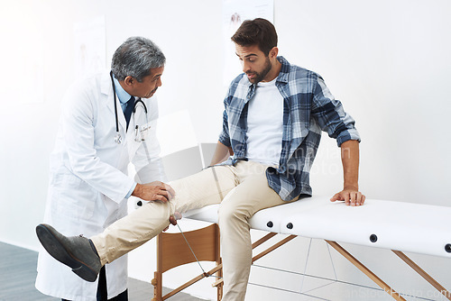 Image of Clinic, patient and doctor with leg exam, consultation and wellness checkup of person at hospital. Medicine, health care expert and man in doctors office consulting medical professional for knee pain