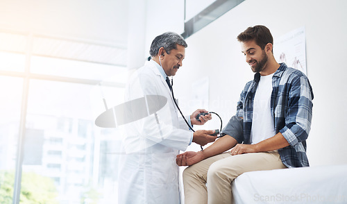 Image of Healthcare, patient and doctor with blood pressure test, help and wellness checkup of person at hospital. Medicine, health care expert and Indian man in doctors office consulting medical professional