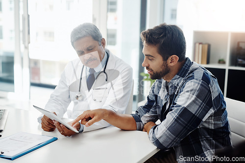 Image of Healthcare, doctor and patient in consultation with tablet, expert advice, discussion and results. Medicine, health care and Indian man in doctors office, internet and consulting medical professional