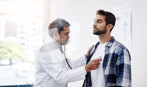 Image of Healthcare, patient and doctor with stethoscope for checkup, help and wellness at hospital. Medicine, health care and heart expert with Indian man in doctors office consulting medical professional.