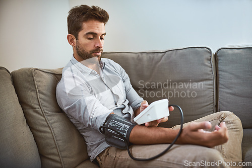 Image of Hypertension, machine and man exam blood pressure in a home sofa or living room for medical or health test. Monitor, reading and person with equipment for chronic disease due to stress