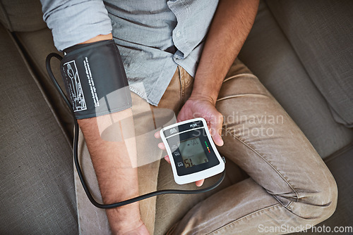 Image of Hypertension, closeup and person with home test for blood pressure on living room sofa for medical or health exam. Monitor, reading and man with equipment for chronic disease or stress from top view
