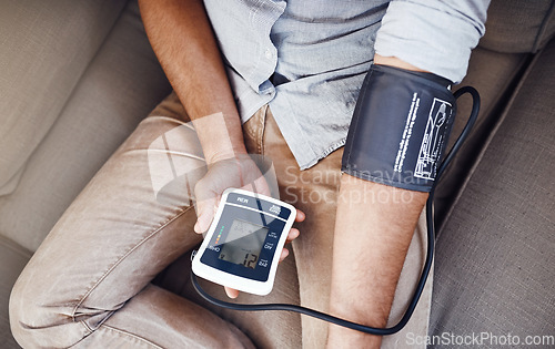 Image of Hypertension, machine and man test blood pressure in a home sofa or living room for medical or health exam. Monitor, reading and person in a lounge equipment for chronic disease due to stress