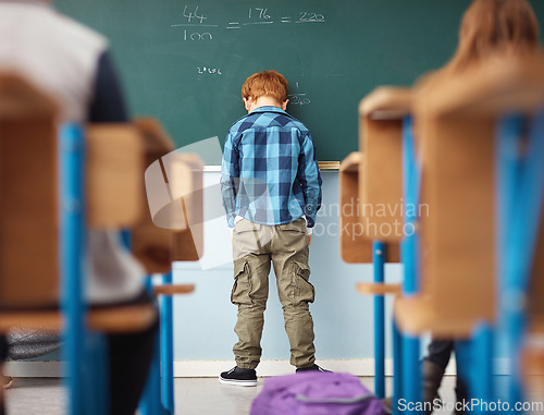 Image of Rear view, boy student in detention with head on chalkboard and in classroom of school building. Anxiety or depressed for time out, math problems to solve and male kid with back to class.