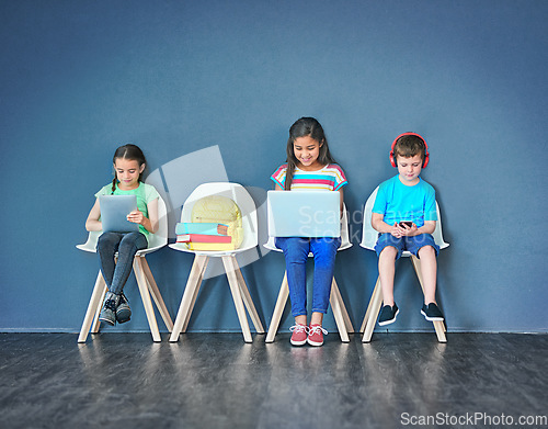 Image of Chairs, children, and technology for learning and education while online for research on internet. Kids or students against a blue mockup wall with laptop, tablet and video on phone in a waiting room