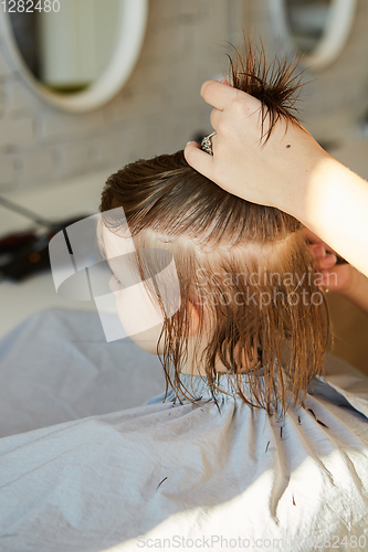 Image of Hairdresser making a hair style to cute little girl.