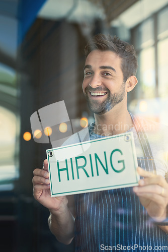 Image of Man with hiring sign, cafe window with recruitment and job opportunity, happy waiter or barista in portrait. Small business, entrepreneur and male owner onboarding, advertising hire at coffee shop