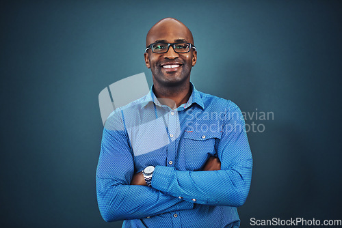 Image of Business, black man and portrait with arms crossed in a studio feeling proud from auditor work. Blue background, smile and African employee with success and leadership vision with glasses and idea