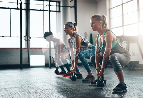 Image of Kettlebell, fitness and women in a gym, training or workout goal with wellness, class or exercise. Female athlete, girls or squat with equipment, sports or relax with healthy lifestyle or challenge