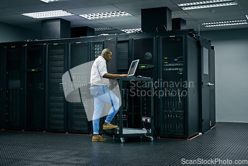 Image of Server room, database and information technology with an engineer man at work on a network mainframe. Computer, programming and cybersecurity with a male technician working in IT support or safety