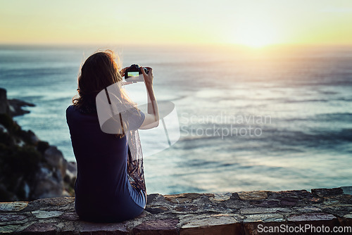 Image of Woman, camera and sunset photography of beach or enjoying time outside or relax for vacation in summer or in nature and ocean view. Sunrise, female photographer and travel blog for holiday outdoors