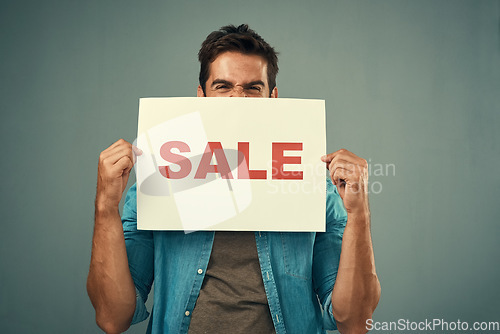 Image of Man, hands and sale sign for advertising, marketing or branding against a grey studio background. Excited male person or model holding billboard or poster for sales, announcement or advertisement