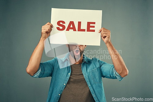 Image of Man, hands and sale sign for advertising, marketing or branding against a grey studio background. Male person, surprise or discount holding board or poster for sales announcement or advertisement