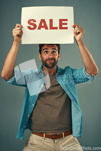 Image of Man, hands and sale on billboard for advertising, marketing or branding against a grey studio background. Male person or realtor holding board, sign or poster for sales announcement or advertisement