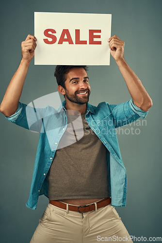 Image of Happy man, sale and billboard poster for advertising, marketing or branding against a grey studio background. Male person or realtor holding board or sign for sales announcement or advertisement