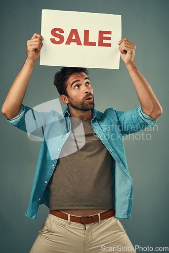 Image of Man, hands and sale on poster for advertising, marketing or branding against a grey studio background. Male person or realtor holding board, sign or billboard for sales announcement or advertisement