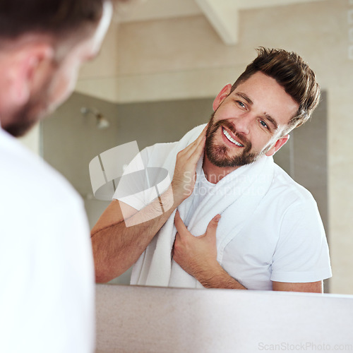 Image of Grooming, face and mirror for man with skincare and self care routine in a bathroom with a smile. Home, reflection and cleaning with a young male person feeling happy from beard growth or dermatology