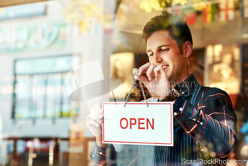 Image of Coffee shop, open sign and a man small business owner standing a glass door for service or hospitality. Cafe, manager or employee with a happy male waiter proud to be opening a new restaurant