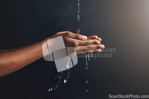 Image of Washing hands, water and person cleaning palm for hygiene isolated in a dark or black studio background. Stream, splash and hand clean for wellness or hydration with germ protection or bacteria