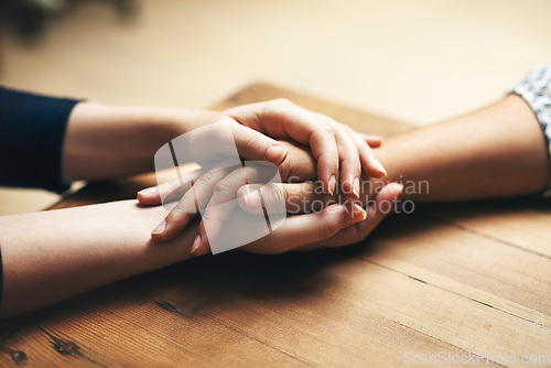 Image of Holding hands, cancer and support of friends, care and empathy together on table in home mockup. Kindness, love and women hold hand for hope, trust or prayer, comfort or compassion, help or unity.
