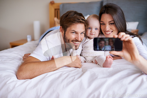 Image of Mother, father and smile for selfie with baby on bed in home for love, care or social media together. Happy family, parents and cute kid taking photograph for memory, happiness and relax in bedroom