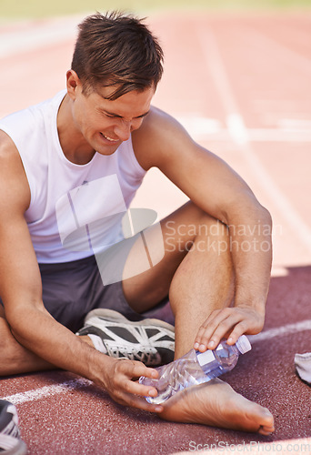 Image of Injury, outdoor and man with water bottle on feet for exercise, running or workout pain at a sports stadium. Athlete person with muscle problem, accident or burnout while training for body fitness