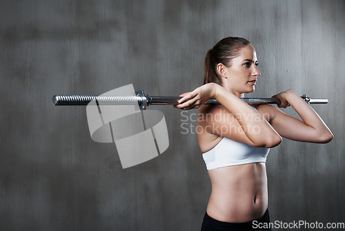 Image of Fitness, exercise and woman with barbell at gym for bodybuilding, strength or endurance on wall background. Weightlifting, training and female with strong mindset at sports center for intense workout