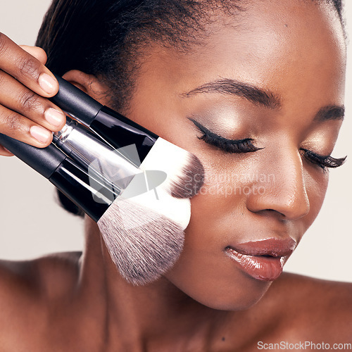 Image of Beauty, makeup and brushes on face, black woman with cosmetic tools in studio with application tool. Skincare, blush and cosmetics, closeup of facial care model with luxury powder on white background