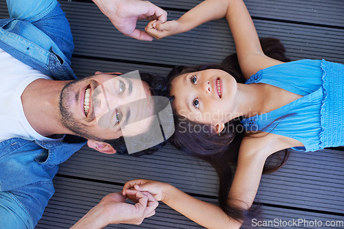 Image of Holding hands, top view and relax father, happy kid or family bonding together for trust, support and solidarity. Fathers Day, floor and face of young kid, youth girl and dad lying on ground