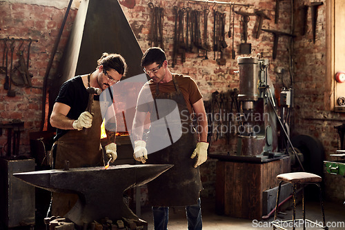 Image of Welding, craftsmen working and in a metal workshop together with protection gear. Collaboration or teamwork, manufacturing and ppe with welder men with hammer work on iron at their workplace