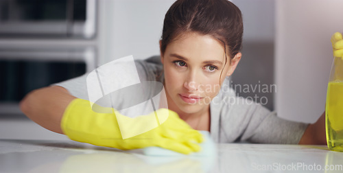 Image of Woman, face and clean kitchen table, chemical detergent spray and cloth, focus and wipe dirt. Safety with gloves, concentration and female cleaner with hygiene, cleaning and disinfecting surface