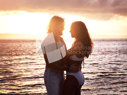 Image of Happy couple, hug and sunset at the beach for love, quality time or bonding together in the water. Man and woman hugging in loving romance, sunrise or sunshine in the ocean for romantic holiday