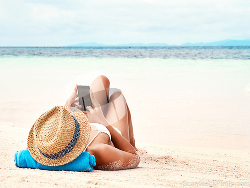 Image of Travel, phone and woman relaxing on the beach scrolling on social media or mobile app on holiday. Rest, tropical and female person laying on sand by ocean networking on cellphone on summer vacation.