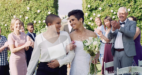 Image of Wedding, happiness and interracial lesbian couple walking down aisle with smile, love and applause. Lgbt marriage, celebration and happy women at ceremony or reception with lgbtq pride and commitment