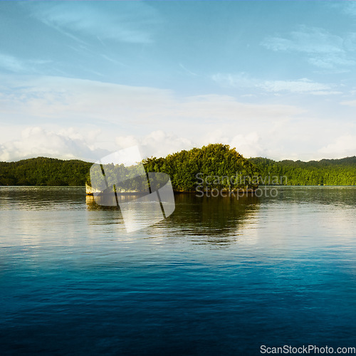 Image of Water, island and natural lake with blue sky and clouds on calm, quiet or peaceful ocean and trees on land. Lakeside with tree in the distance and mockup space in nature view of scenic environment