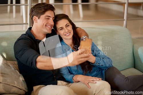 Image of Young couple, sofa and selfie in home with smile, hug or happiness for love, care and web app. Man, woman and happy for photography, profile picture and social media with bond, relax and lounge couch