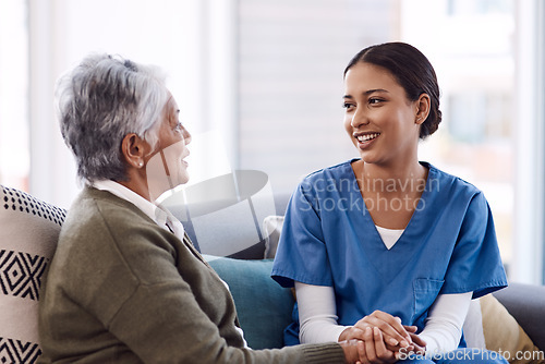 Image of Communication, caregiver and elderly woman on lounge holding hands in living room for support. Care or healthcare, happy people and female nurse talking or consulting with a patient on a sofa.