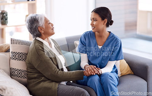 Image of Support, caregiver holding hands with a senior woman and on sofa at nursing home for care. Consulting or healthcare conversation, communication with nurse and elderly female patient talking on couch