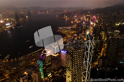 Image of Aerial, skyscrapers and night city of office buildings with lake, lights and riverside in the outdoors. Drone view of CBD, architecture or cityscape and late infrastructure lighting of a urban town