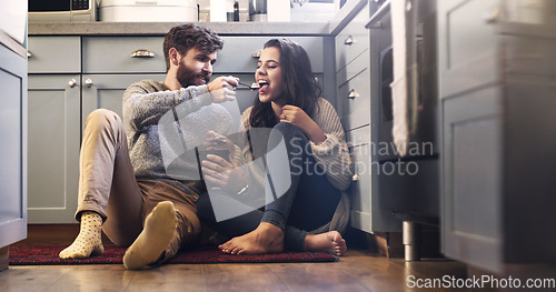 Image of Ice cream, kitchen and couple on floor in home for bonding, relaxing and quality time together. Love, relationship and happy man and woman with sweet treats, dessert and luxury snack for romance