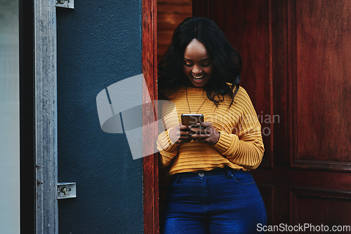 Image of Door, phone and woman on social media, texting and happy while reading message in front of house. Smartphone, influencer and african female online for blog, networking or accommodation app review