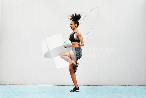 Image of Jump, skipping rope and training with woman in stadium for sports, workout practice and cardio. Performance, health and body with female athlete jumping on track for strong, mockup space and exercise