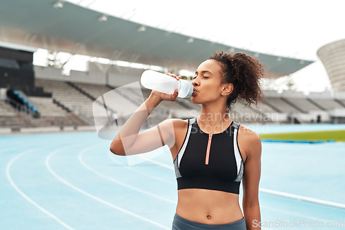 Image of Fitness, running and woman on track drinking from bottle at stadium, relax during marathon training or exercise. Workout time, health and wellness, healthy female sports runner at area with water.