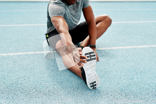 Image of Athlete, sitting and track for stretching legs to start training, exercise or running for fitness outdoor. Man, runner and warm up for muscle, body and wellness at stadium for race, contest or sports