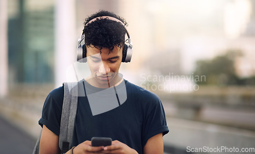 Image of Phone, music and headphones with a man in the city, streaming an audio subscription service outdoor. Mobile, social media and backpack with a young male tourist outside in an urban town for travel